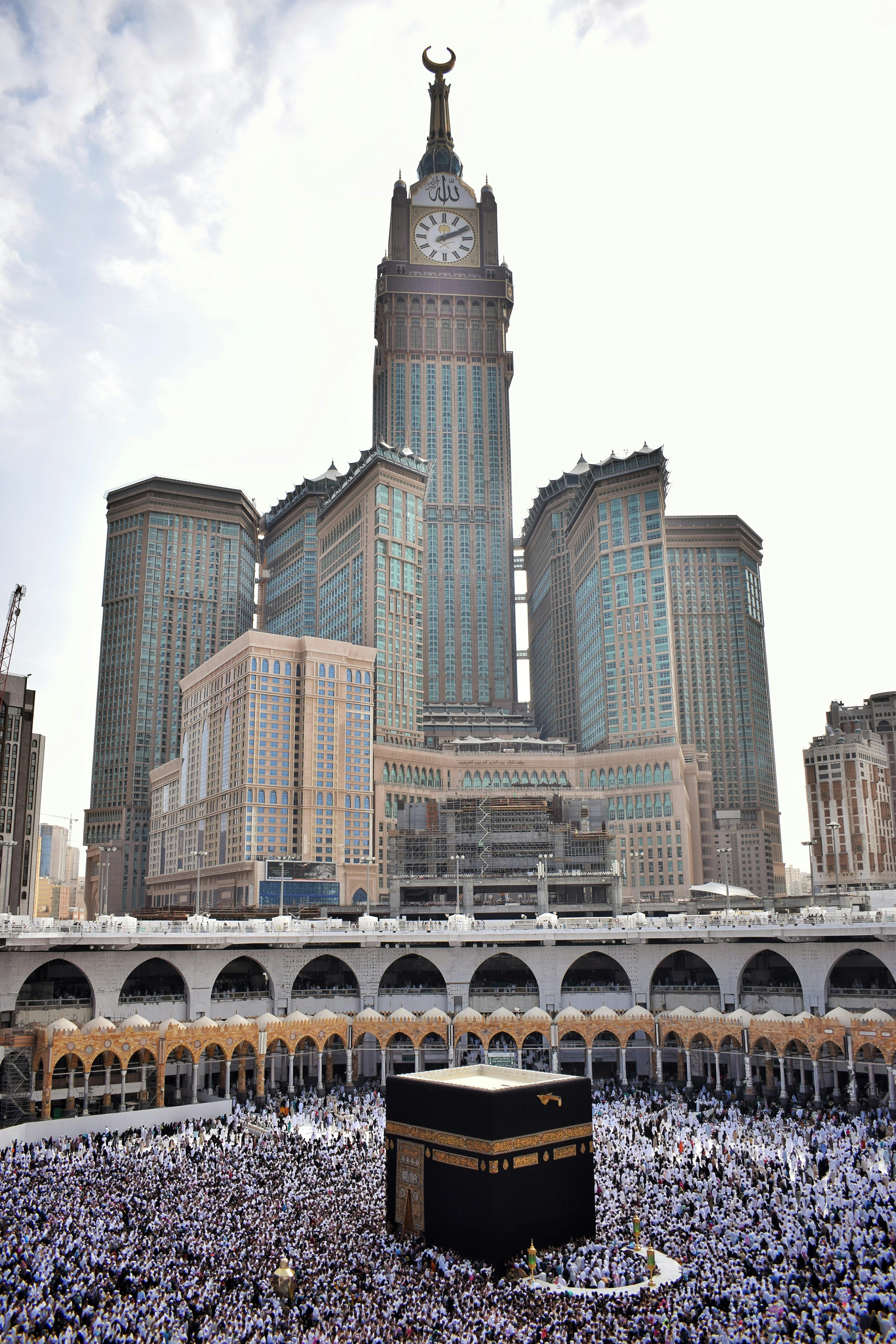 A beautiful panoramic view of the Masjid Al Haram in Makkah, with the Kaaba at its center, under a clear blue sky.
